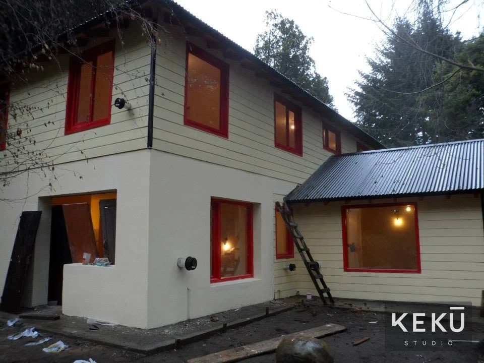 Vista de la fachada de una vivienda con aberturas rojas